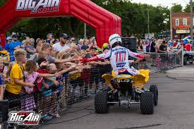 A person on a four wheeler in front of a crowd.