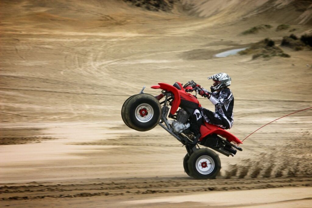 A person on a red and black atv in the dirt.